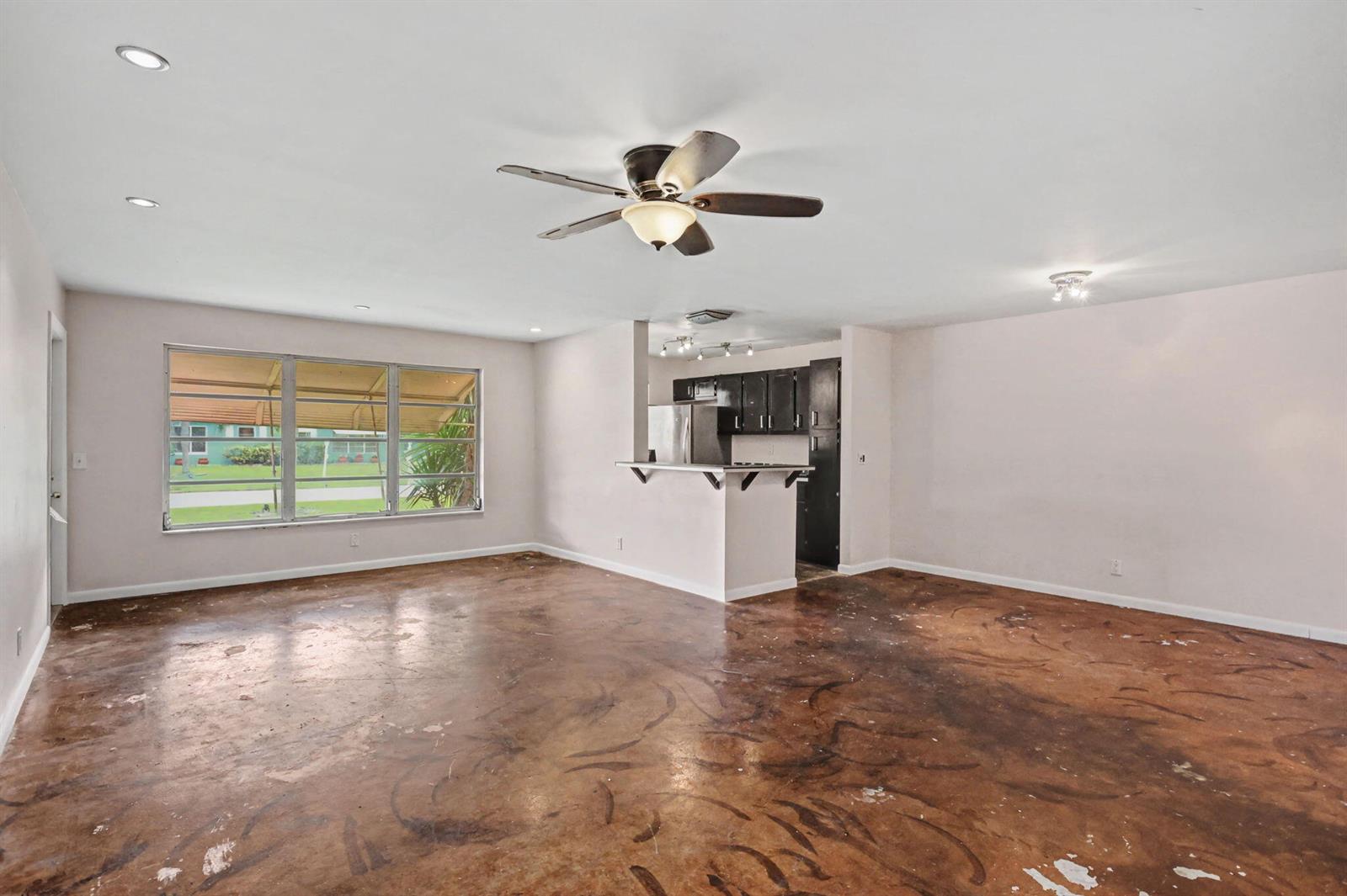 A living room with a ceiling fan, stained concrete floors, and an open kitchen area — 275 South Boulevard # C, Boynton Beach FL 33435, BOYNTON BEACH, FL