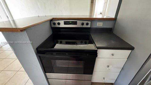A stainless steel electric range is positioned between a kitchen counter and white drawers — FORT LAUDERDALE, FL