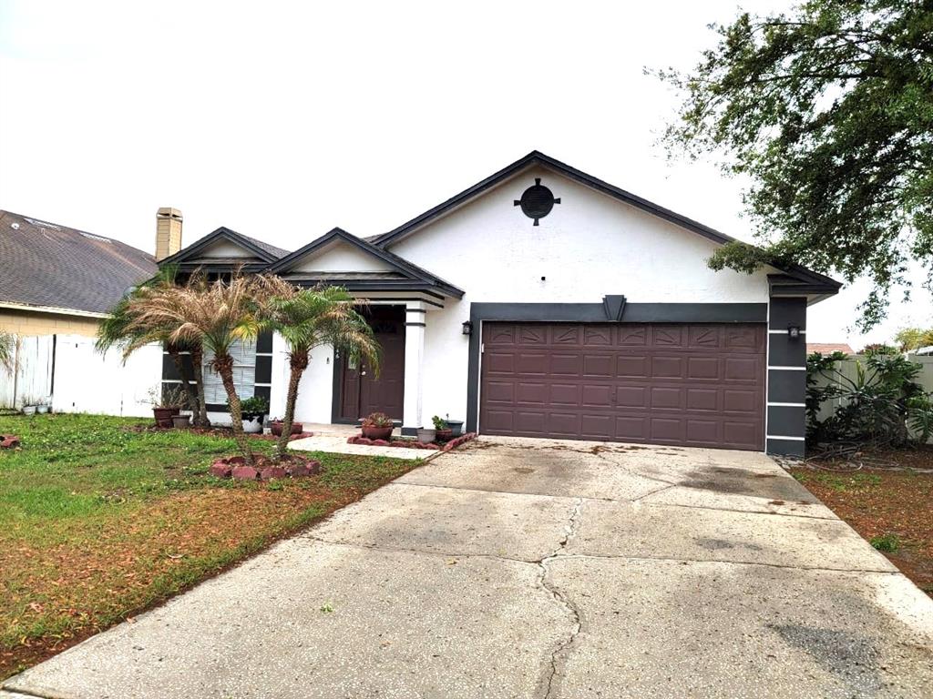 A single-story house with a white exterior, dark trim, a brown garage door, and palm trees — 1946 EXCALIBUR DRIVE, ORLANDO, FL
