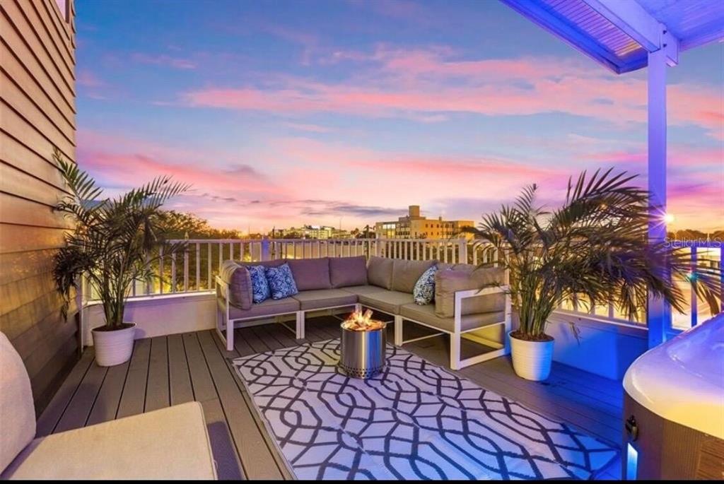 A rooftop deck features a sectional sofa, a fire pit, and a hot tub at sunset — 343 8TH STREET N, ST PETERSBURG, FL