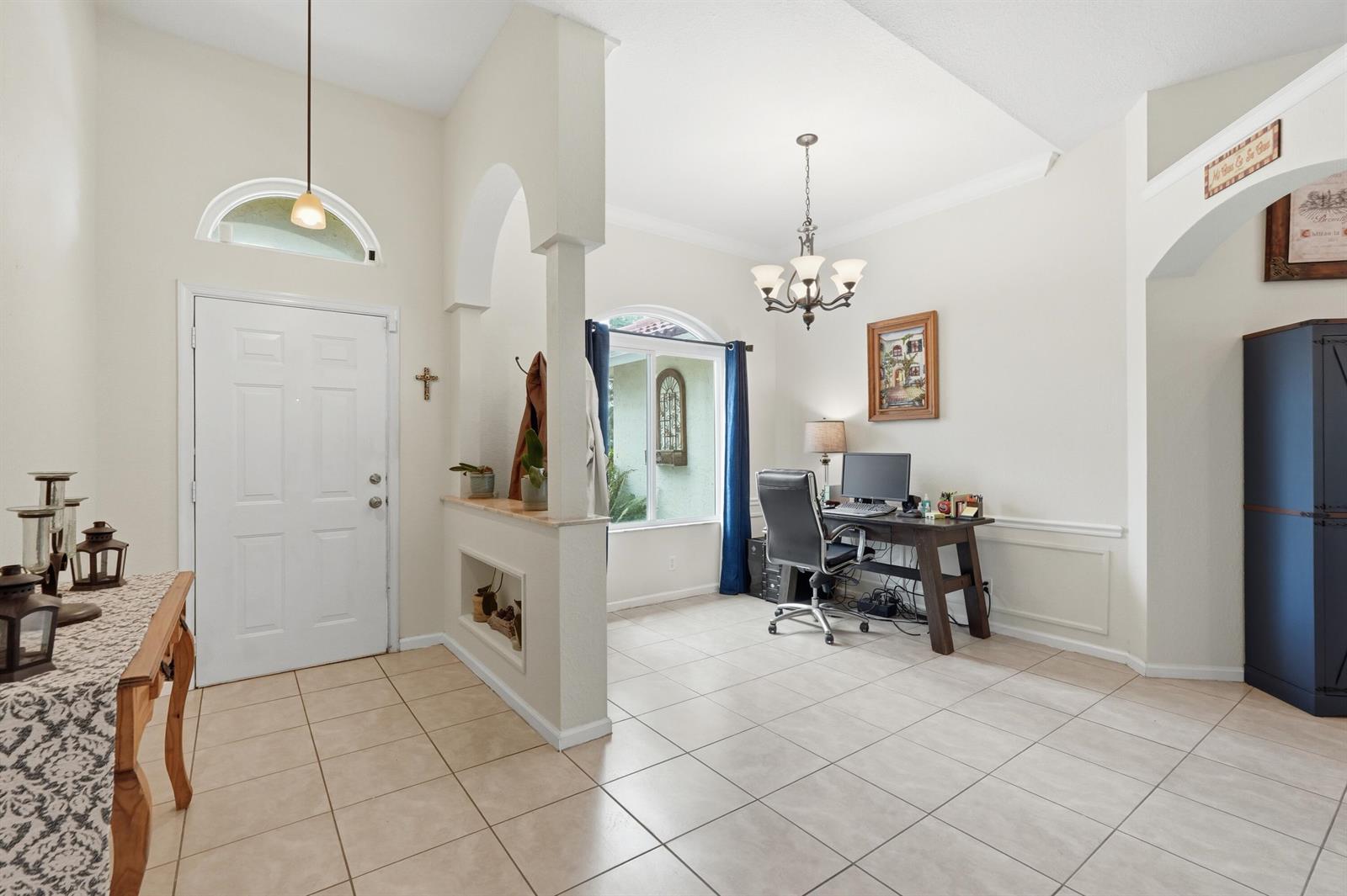 An entryway leads into a tiled home office space with an arched wall partition — 15327 64th Place N, FL 33470, FL