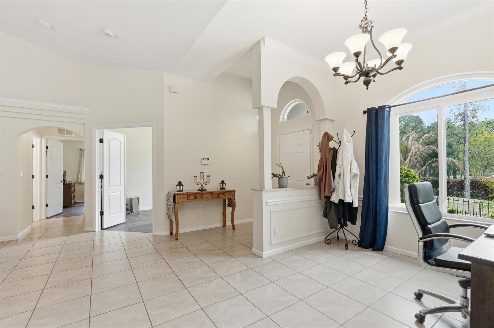 A bright home office features tile flooring, an arched entryway, and a large window — 15327 64th Place N, FL 33470, FL