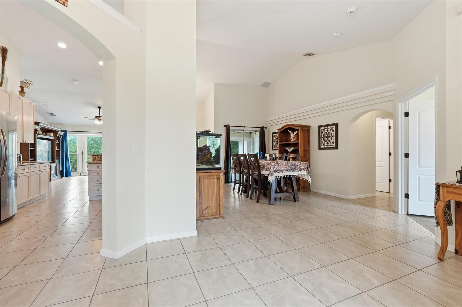 An open-concept living area features tile flooring, a dining set, and an adjacent kitchen — 15327 64th Place N, FL 33470, FL