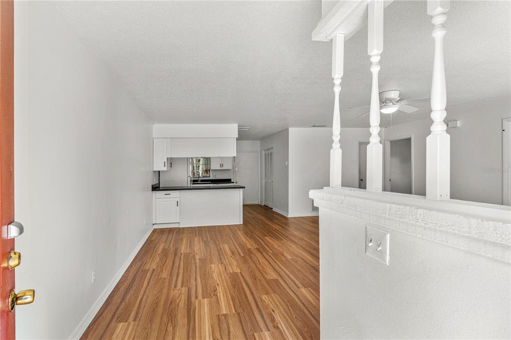 A view from an entryway looking toward a kitchen with white cabinets and wood flooring — 2304 INDIA PALM DRIVE, EDGEWATER, FL