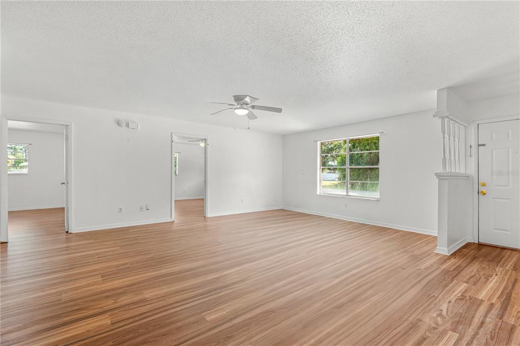 An empty living room with white walls, light wood-look flooring, and a ceiling fan — 2304 INDIA PALM DRIVE, EDGEWATER, FL