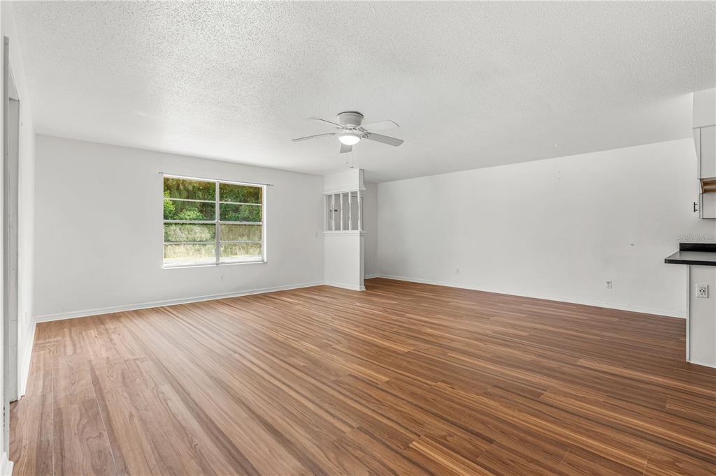 An empty living room features wood-look flooring, white walls, and a ceiling fan — 2304 INDIA PALM DRIVE, EDGEWATER, FL