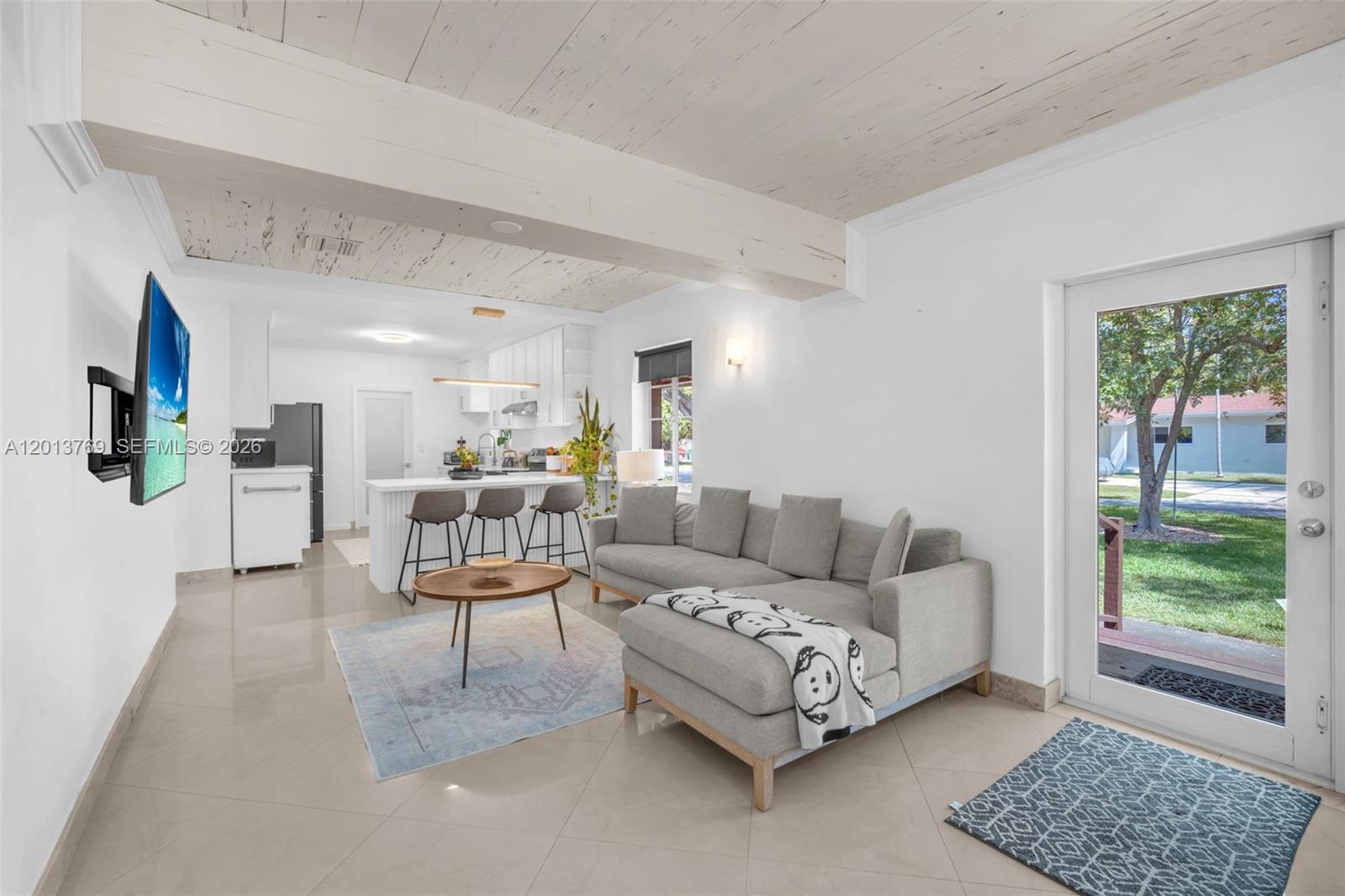 A living room with a sectional sofa, coffee table, and open kitchen with bar seating — 470 NE 113th St # 1, Miami FL 33161, MIAMI, FL