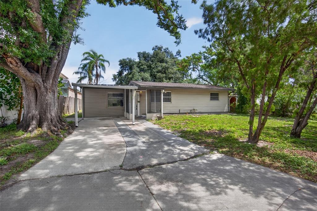A single-story house with beige siding, a carport, and a large tree in the yard — 3615 W ROGERS AVENUE, TAMPA, FL