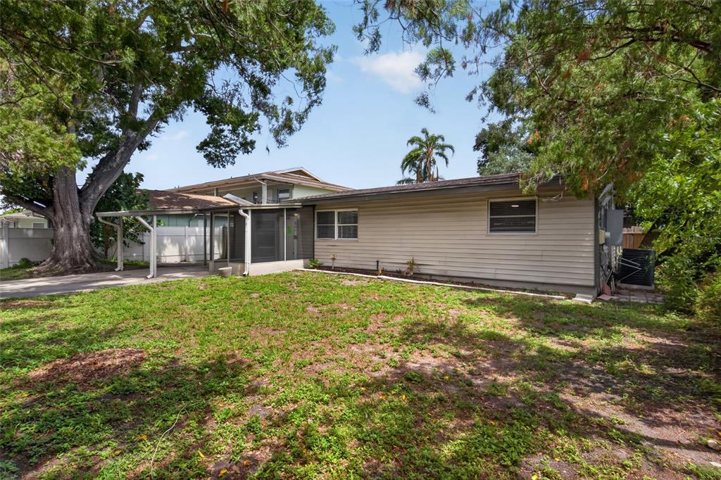 A single-story house with light-colored siding, a carport, and a screened-in porch — 3615 W ROGERS AVENUE, TAMPA, FL