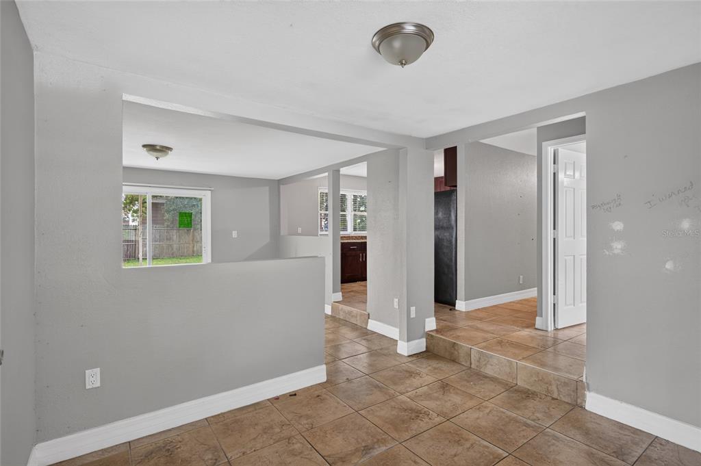 A living area with tile flooring, a half wall, and a view into the kitchen — 3615 W ROGERS AVENUE, TAMPA, FL