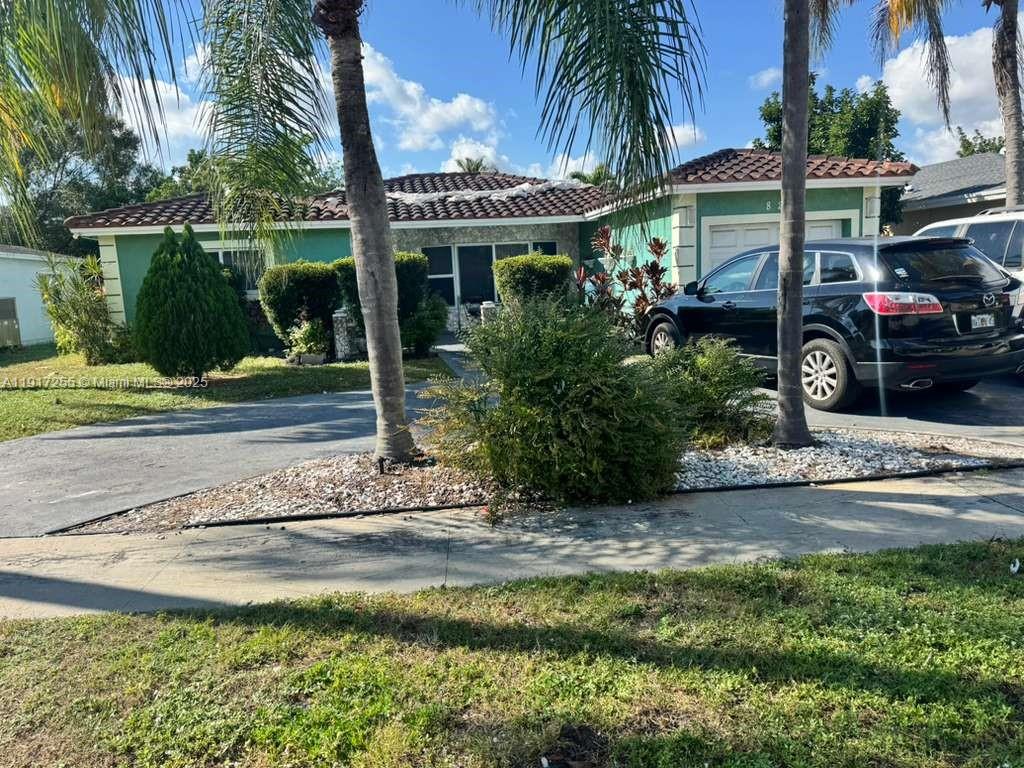 A single-story house with a green exterior, tile roof, and a driveway with a car — 820 SW 49th Ter, Margate FL 33068, MARGATE, FL