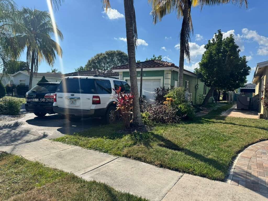 A white SUV is parked in the driveway of a single-story green house — 820 SW 49th Ter, Margate FL 33068, MARGATE, FL
