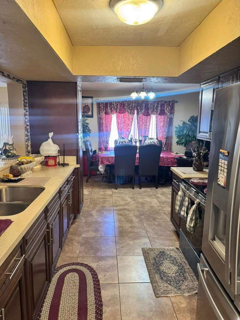 A kitchen with dark wood cabinets and tile flooring leads into a formal dining area — 820 SW 49th Ter, Margate FL 33068, MARGATE, FL