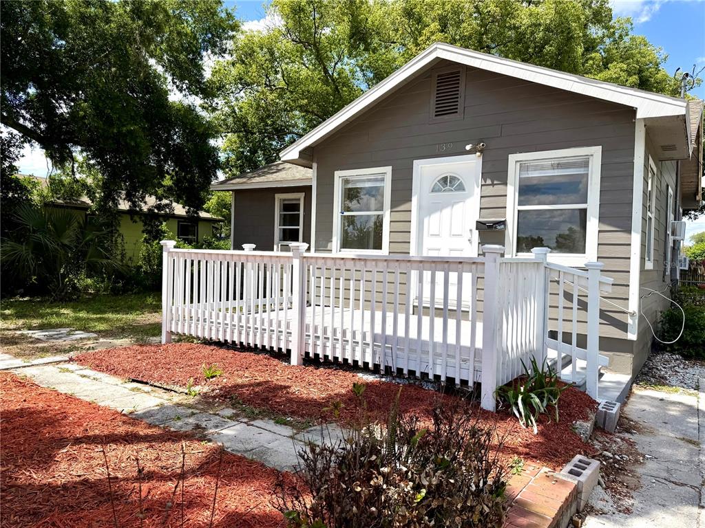 A small gray house with a white front porch and red mulch landscaping — 139 AVENUE G SE, WINTER HAVEN, FL