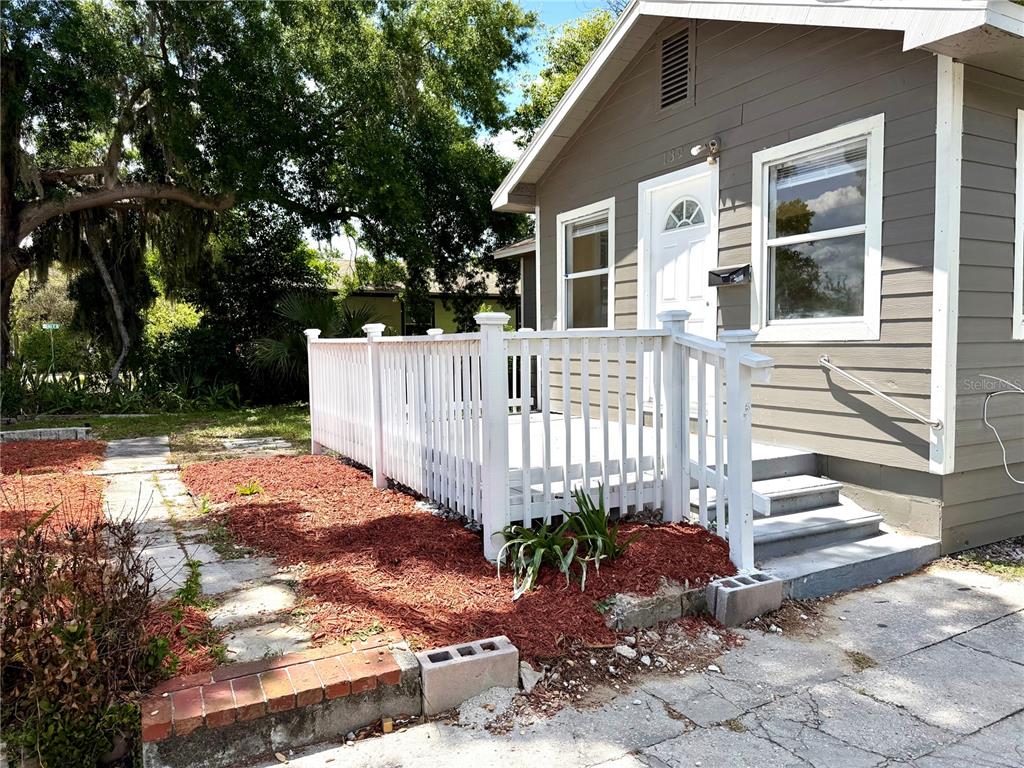 A gray house features a white wooden deck, stairs, and a red mulch garden bed — 139 AVENUE G SE, WINTER HAVEN, FL