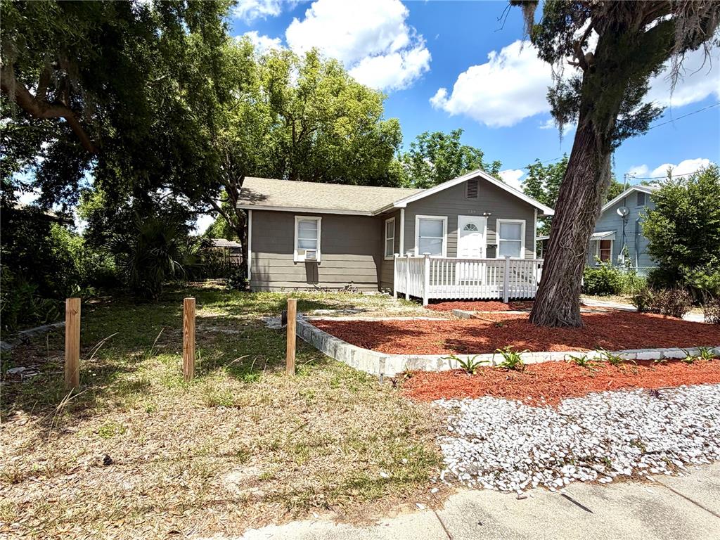 A single-story house with gray siding and a white front porch sits behind a tree — 139 AVENUE G SE, WINTER HAVEN, FL