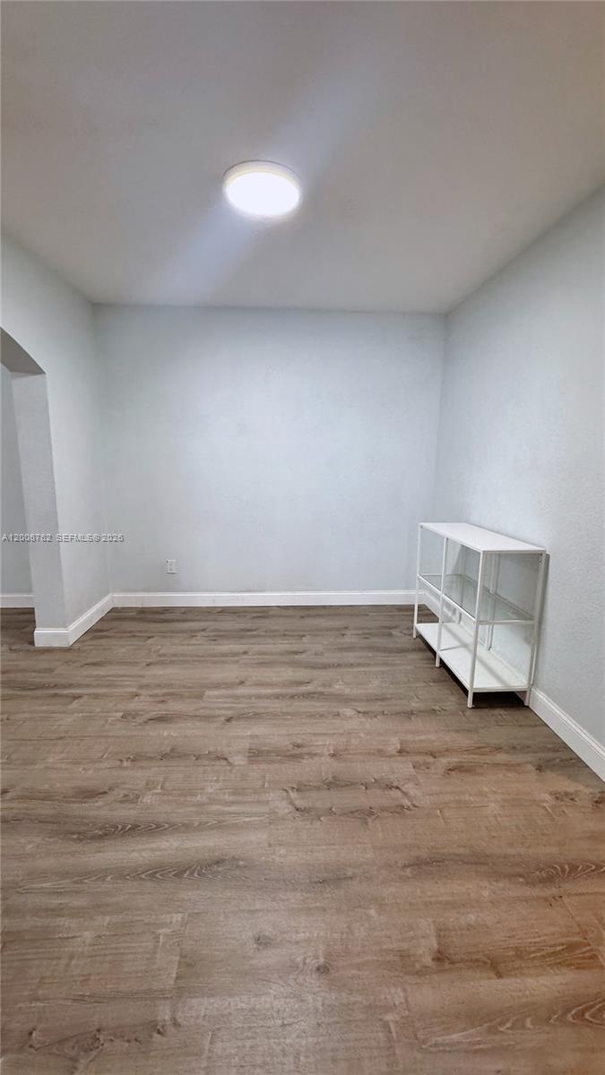 An empty room features light blue walls, wood-look flooring, and a white metal shelving unit — 15810 SW 40th St # 57, Miramar FL 33027, MIRAMAR, FL