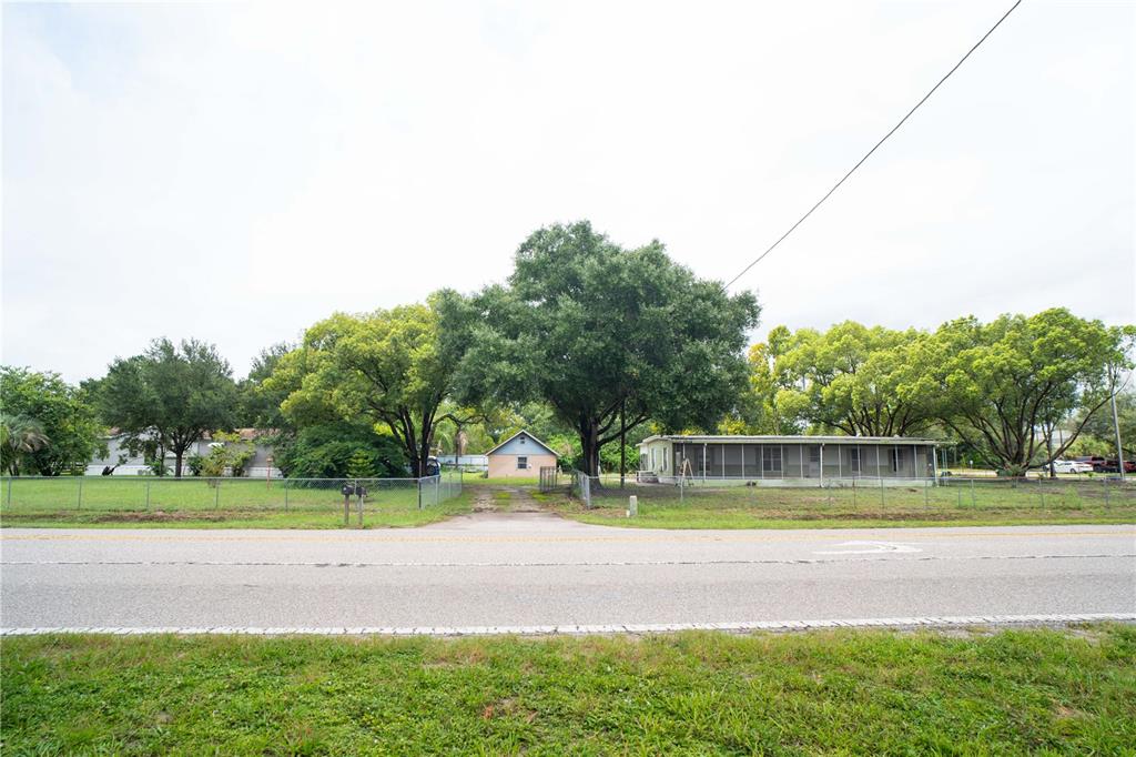 A view of a property featuring a small house, a mobile home, and large trees — 2014 GUNN HIGHWAY, ODESSA, FL