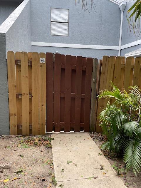 A wooden gate separates two sections of a privacy fence in front of a building — 8 Crossings Circle # A, Boynton Beach FL 33435, BOYNTON BEACH, FL