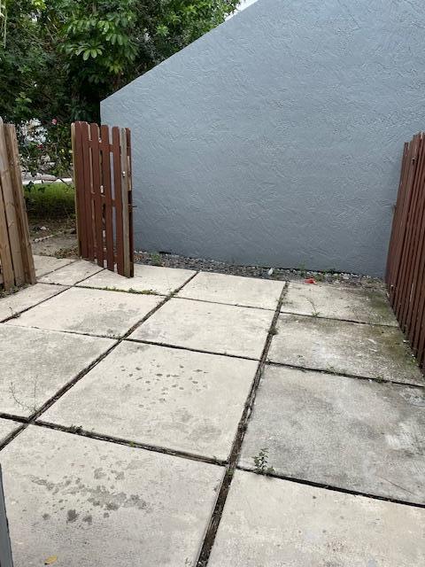 A concrete patio area is enclosed by wooden fences and a gray stucco wall — 8 Crossings Circle # A, Boynton Beach FL 33435, BOYNTON BEACH, FL