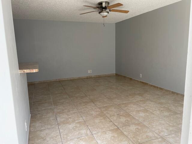 An empty room features gray walls, a ceiling fan, and light-colored square floor tiles — 8 Crossings Circle # A, Boynton Beach FL 33435, BOYNTON BEACH, FL