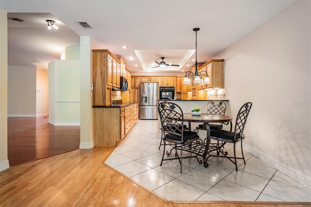 A kitchen with wood cabinets and stainless steel appliances sits beside a tiled dining area — 10133 COLLAR DRIVE, SAN ANTONIO, FL
