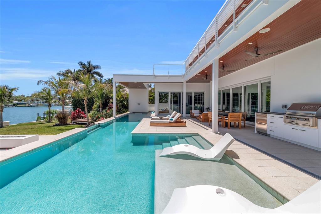 A modern waterfront home features a swimming pool with lounge chairs and an outdoor kitchen — 3631 SAN REMO TERRACE, SARASOTA, FL