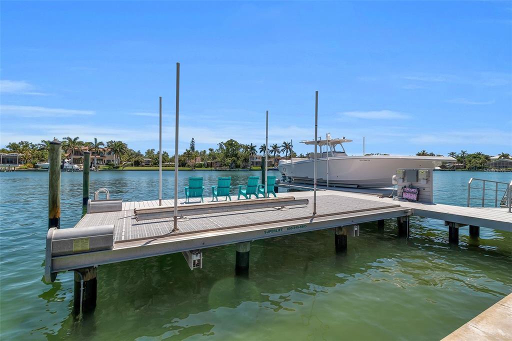 A boat lift with four chairs sits on a dock over a canal — 3631 SAN REMO TERRACE, SARASOTA, FL