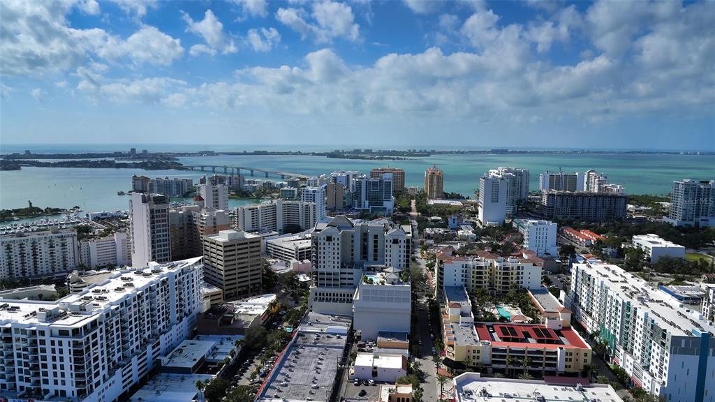 An aerial view shows a dense city skyline with high-rise buildings overlooking a large bay — 100 CENTRAL AVENUE UNIT K817, SARASOTA, FL