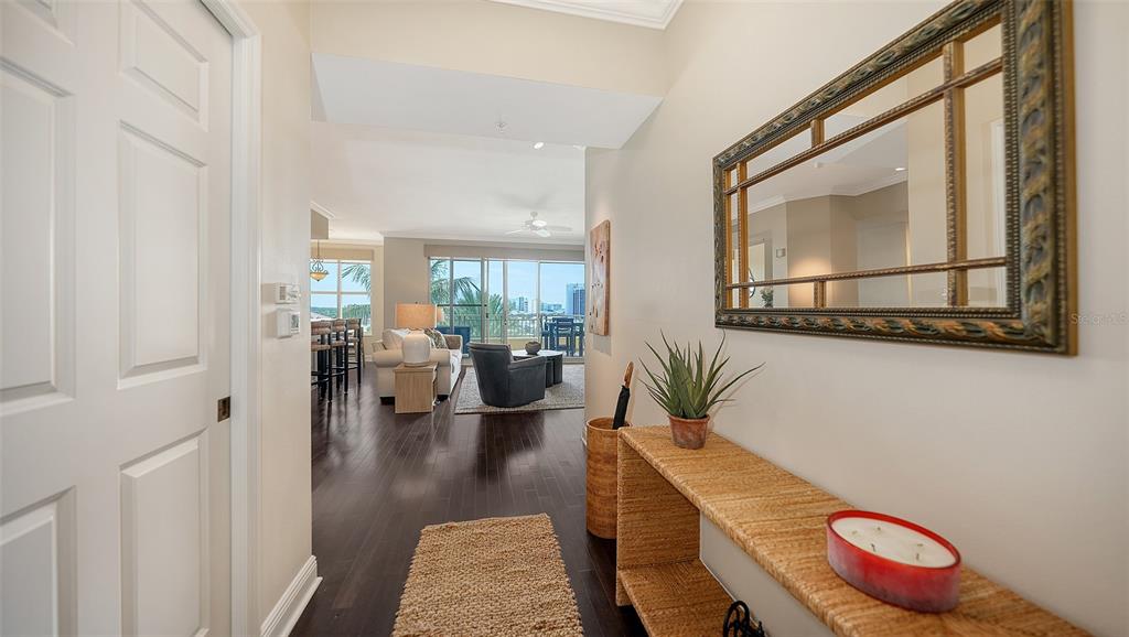 A hallway with dark wood floors leads into a living area with a balcony view — 100 CENTRAL AVENUE UNIT K817, SARASOTA, FL