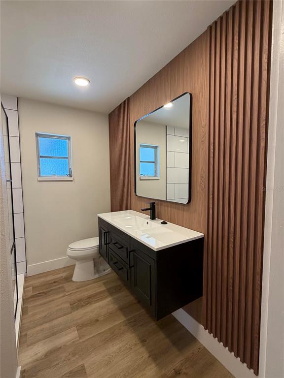 A bathroom features a floating vanity, a slatted wood accent wall, and a rectangular mirror — 1301 NICHOLS DRIVE, TAVARES, FL