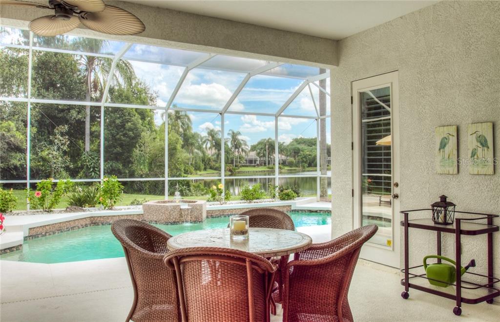 A covered patio with a dining set, a swimming pool, and a view of a lake — 6939 LENNOX PLACE, UNIVERSITY PARK, FL