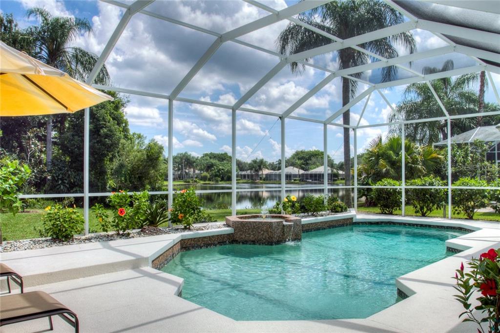 A screened-in pool and spa overlook a lake surrounded by trees and residential homes — 6939 LENNOX PLACE, UNIVERSITY PARK, FL