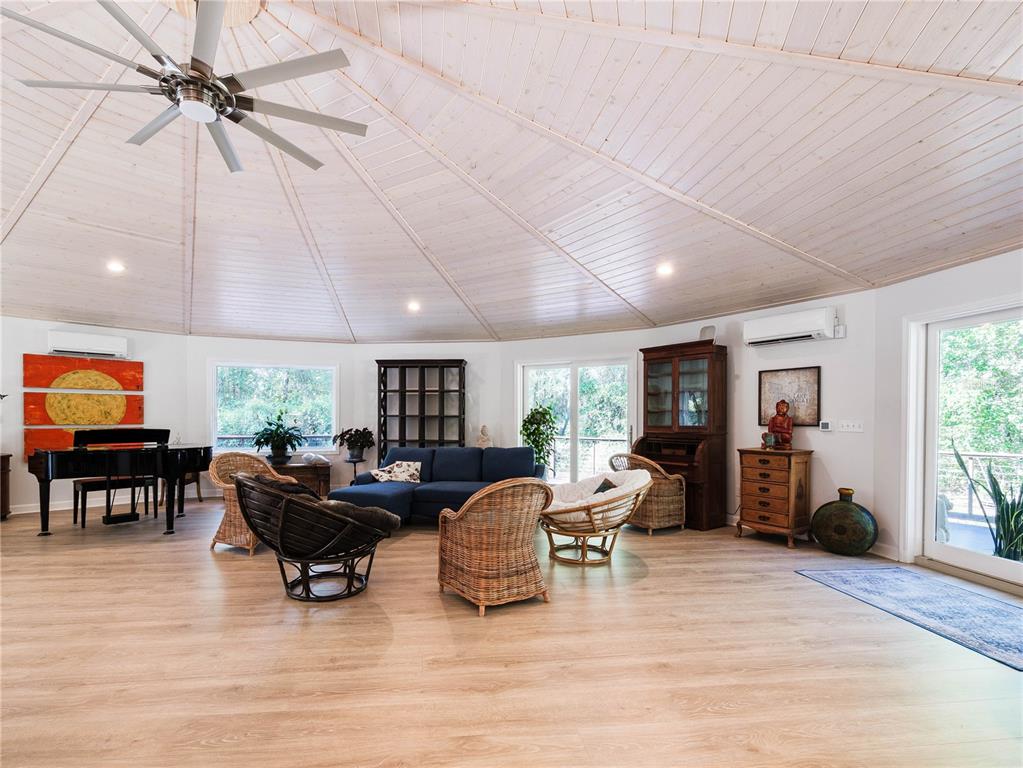A spacious circular living room features a vaulted wood ceiling, light flooring, and wicker furniture — 13797 NE 199TH STREET, WALDO, FL