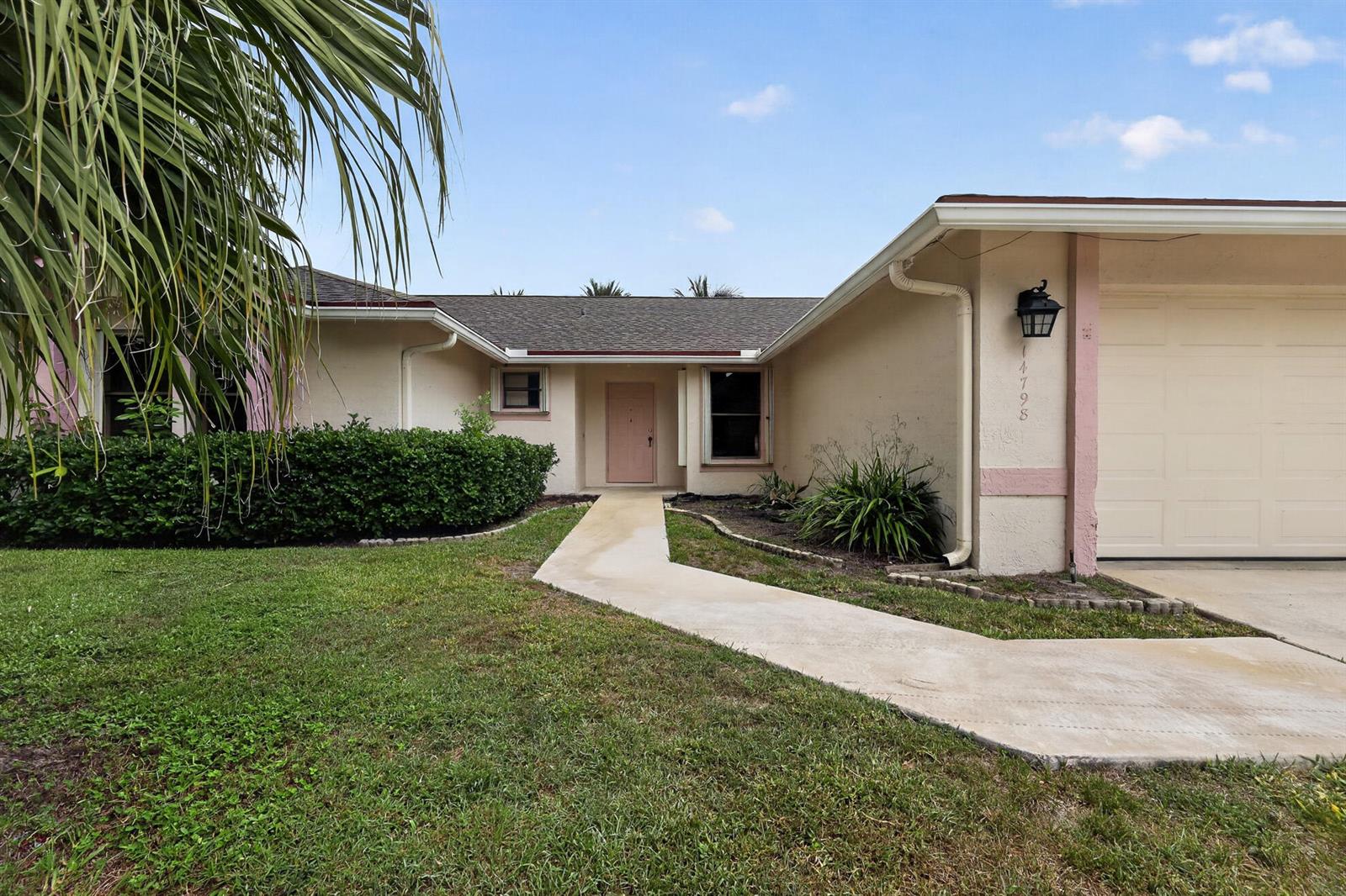 A single-story house with a beige exterior, a pink front door, and a concrete walkway — 14798 Paddock Drive, Wellington FL 33414, WELLINGTON, FL