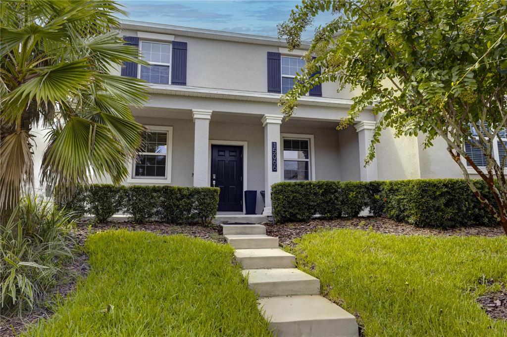 A two-story house with a covered front porch, dark shutters, and a concrete walkway — 15066 BOOK CLUB ROAD, WINTER GARDEN, FL