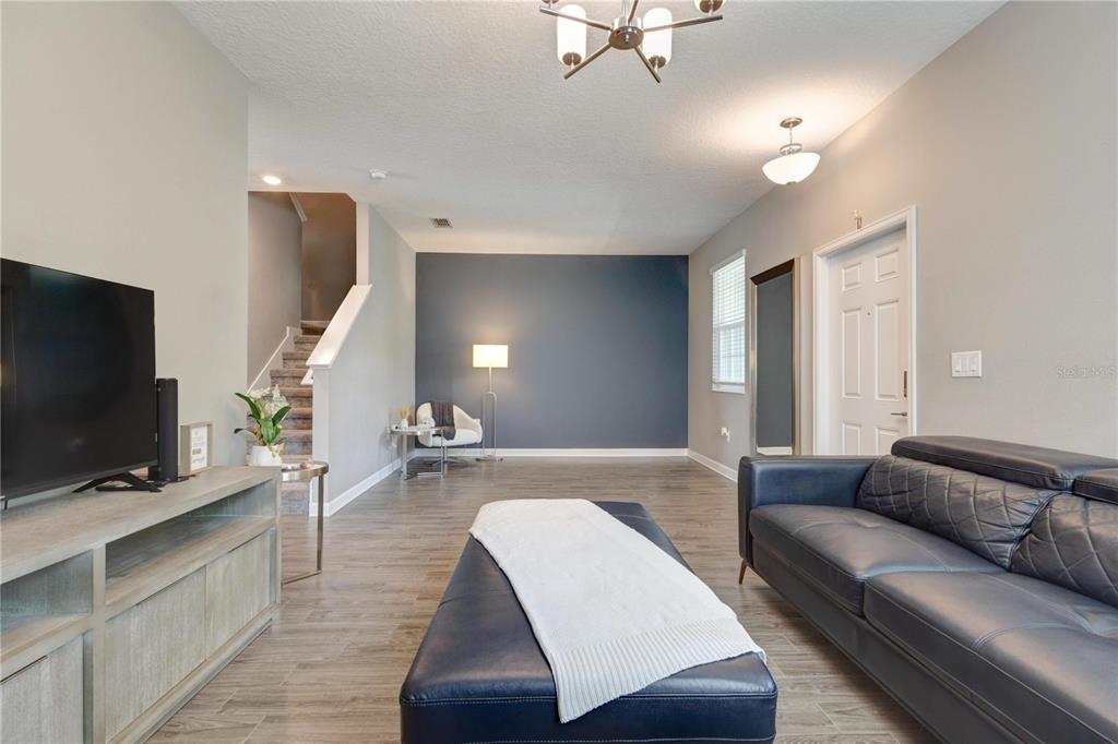 A living room features gray wood-look tile flooring, a dark blue accent wall, and stairs — 15066 BOOK CLUB ROAD, WINTER GARDEN, FL