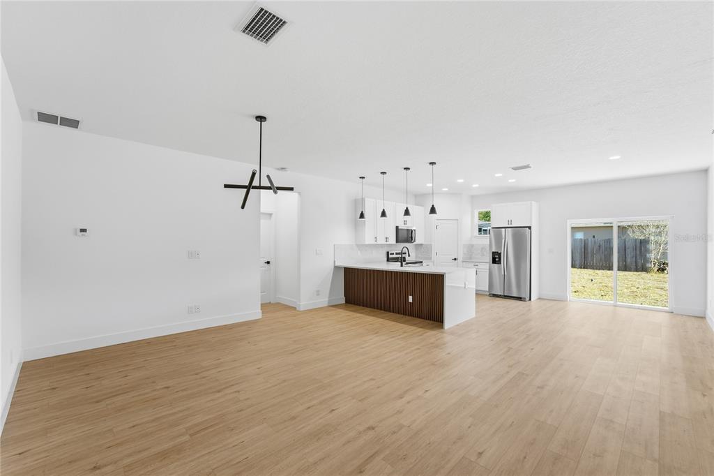 An open-concept kitchen and living area features light wood flooring, white cabinetry, and a peninsula — 7109 N TAVOLI TERRACE, CITRUS SPRINGS, FL