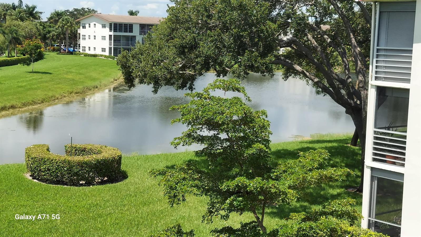 An exterior view shows a pond surrounded by green lawns, trees, and apartment buildings — 160 Preston D # 160, Boca Raton FL 33434, BOCA RATON, FL