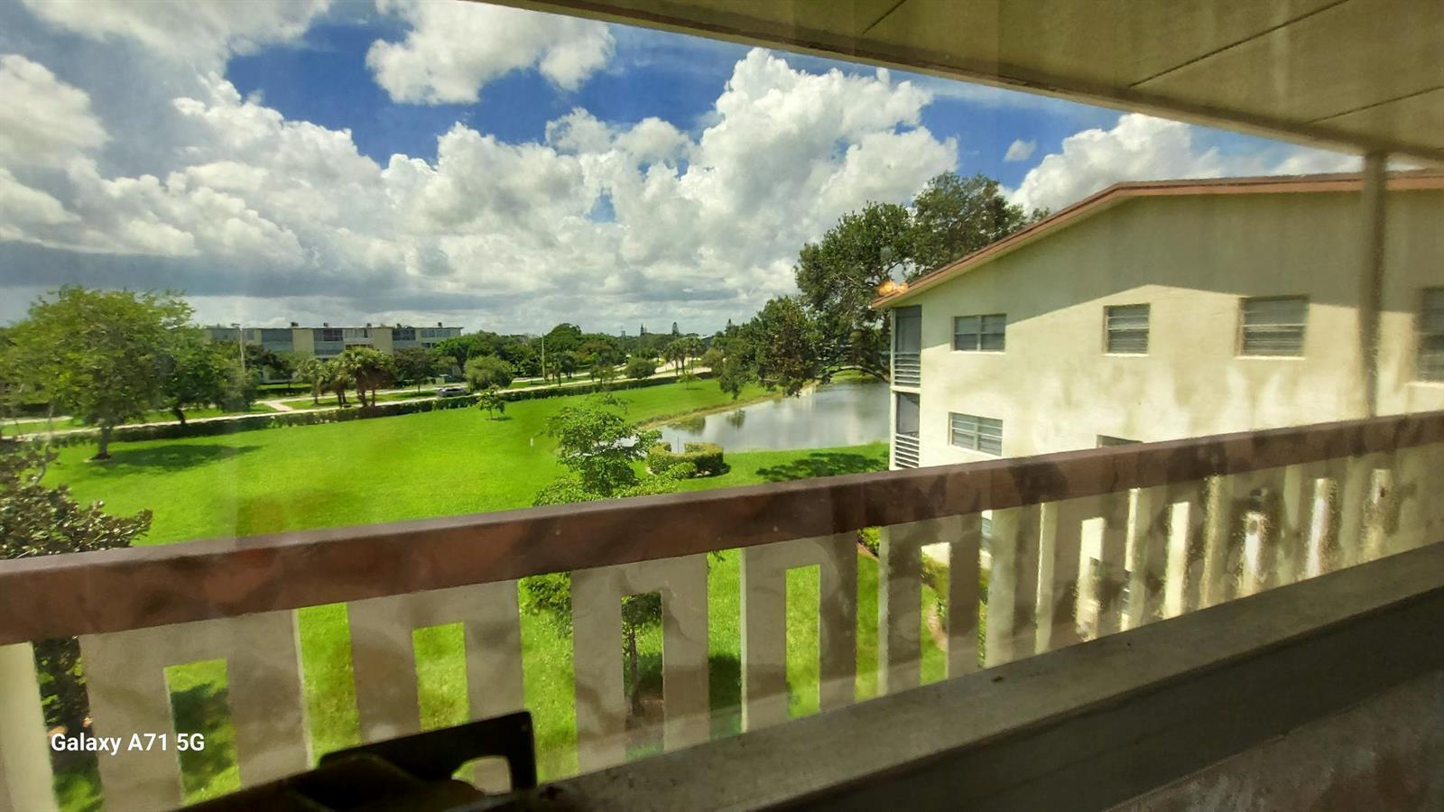 A view from a balcony overlooking a grassy lawn, a small pond, and apartment buildings — 160 Preston D # 160, Boca Raton FL 33434, BOCA RATON, FL