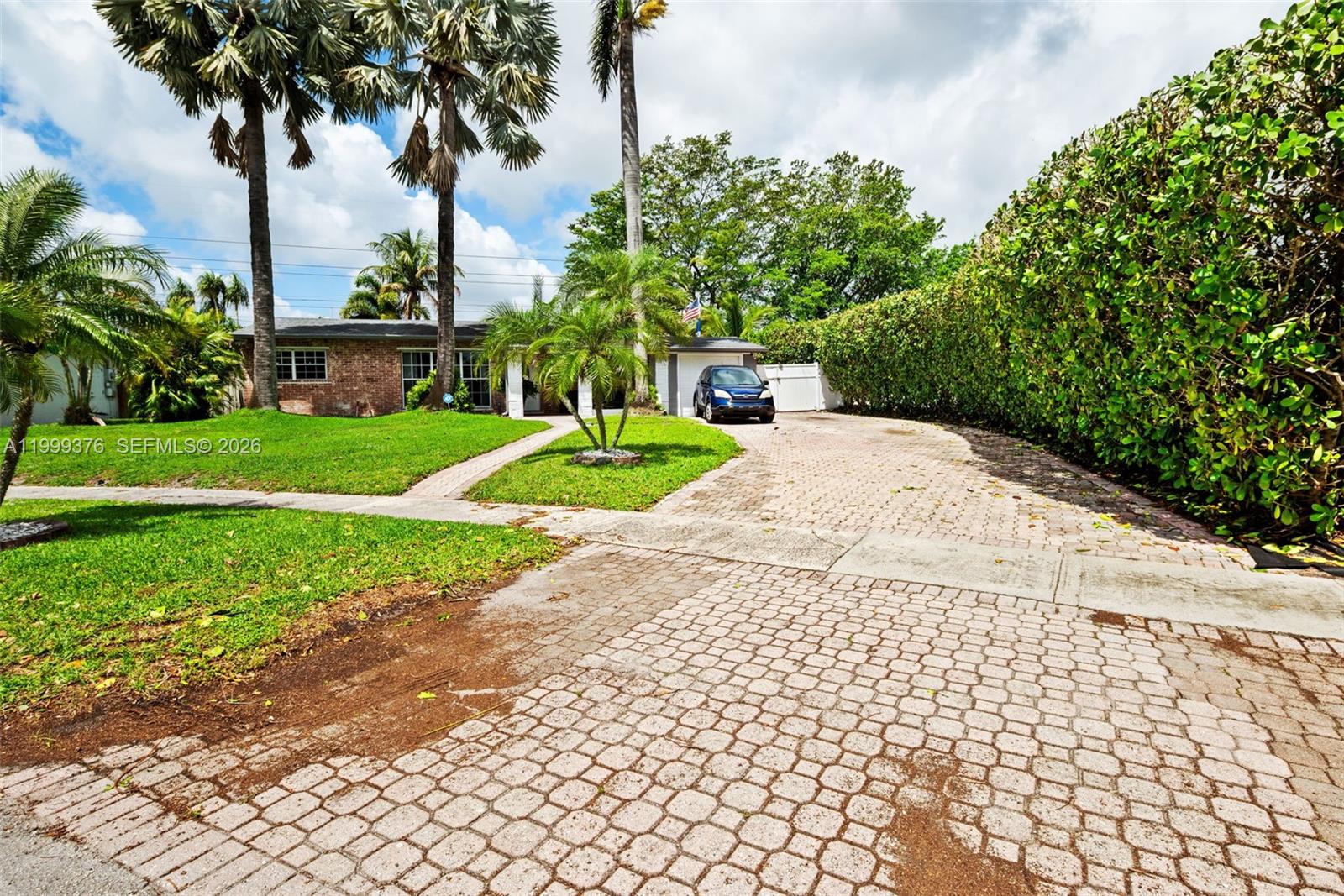 A brick-paved driveway leads to a single-story brick house with palm trees and landscaping — 911 SW 51st Ave, Plantation FL 33317, PLANTATION, FL