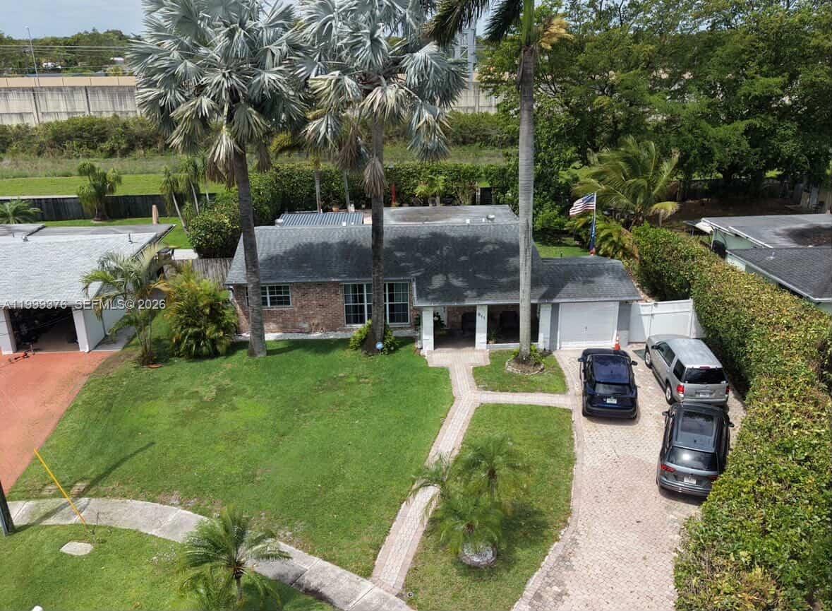 An aerial view of a single-story house with a brick facade, palm trees, and driveway — 911 SW 51st Ave, Plantation FL 33317, PLANTATION, FL