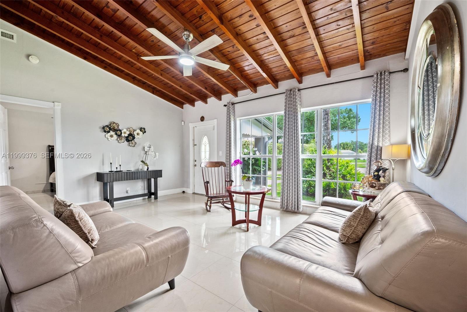 A living room features a wood-beamed ceiling, tile flooring, and two leather sofas — 911 SW 51st Ave, Plantation FL 33317, PLANTATION, FL