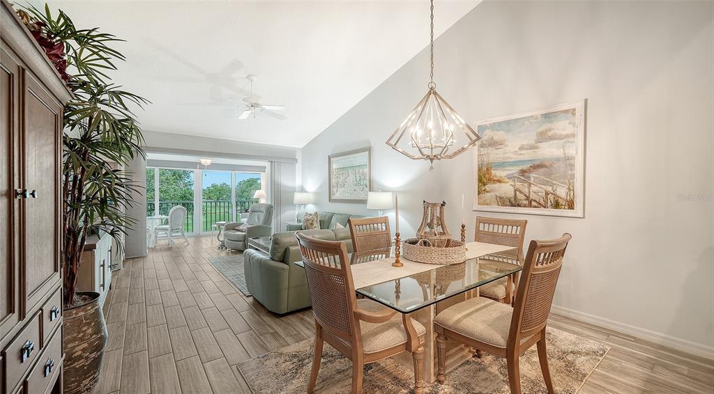 A dining area with a glass table and chandelier opens into a living room space — 8750 OLDE HICKORY AVENUE UNIT 9305, SARASOTA, FL