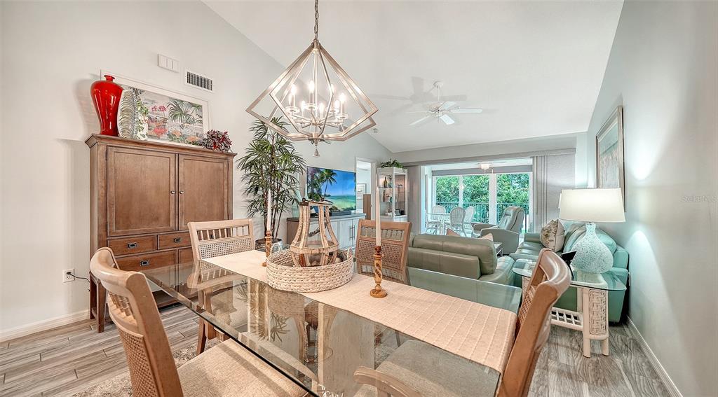 A dining area with a glass table and chandelier opens into a living room space — 8750 OLDE HICKORY AVENUE UNIT 9305, SARASOTA, FL