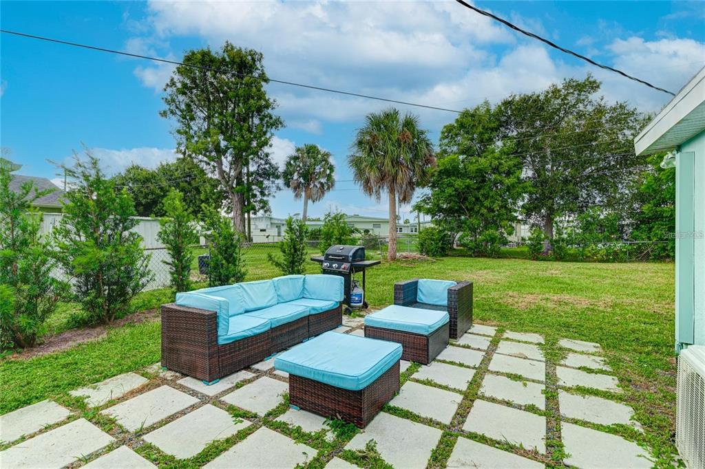 A backyard patio features a wicker sectional sofa, ottoman, and grill on concrete pavers — 1023 ROBERTA STREET, VENICE, FL