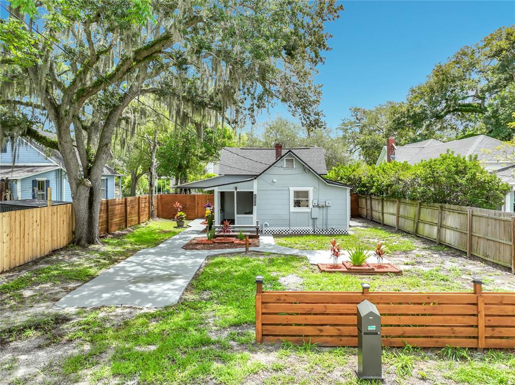 A light blue house with a gray roof stands behind a wooden fence and walkway — 306 S ELM AVENUE, SANFORD, FL