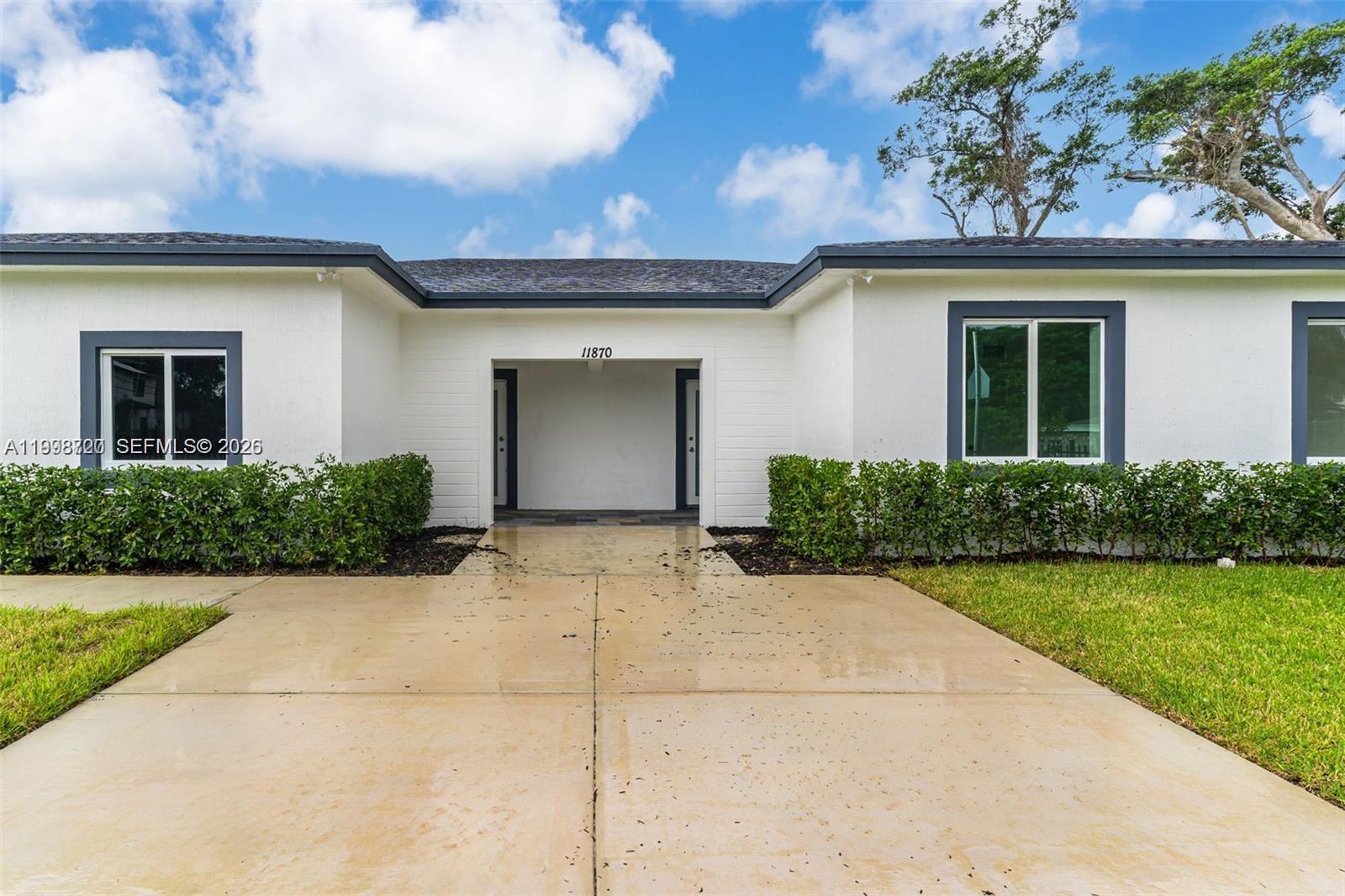 The exterior of a white house features a central recessed entryway and a concrete driveway — 11870 SW 220th St # A, Miami FL 33170, MIAMI, FL