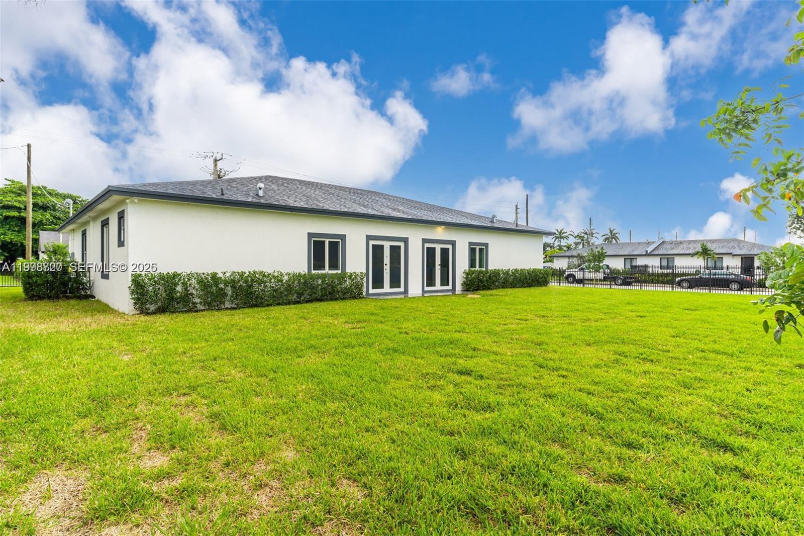 The exterior of a white single-story house features a gray roof and a grassy yard — 11870 SW 220th St # A, Miami FL 33170, MIAMI, FL