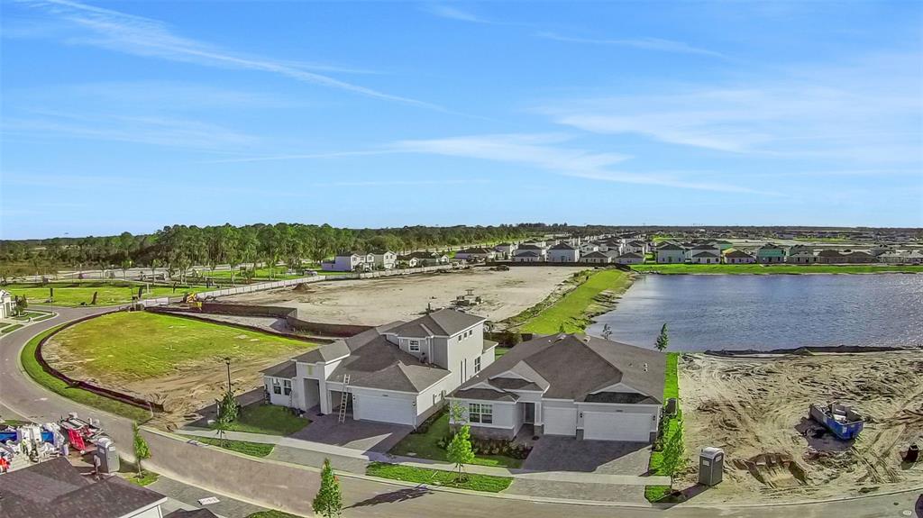 An aerial view shows two newly constructed houses next to a lake and construction site — 10725 NW SUNCREST LOOP, PORT ST LUCIE, FL